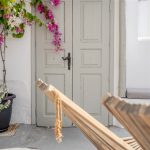 Kampanario Villa Santorini iç avlu, ahşap deck chair ve bougainvillea ile çerçeveli giriş kapısı