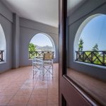 Maistros Village Santorini oda balkonu, arch'lı pencereler ve uzaktan deniz manzarası