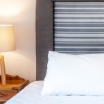 Maistros Village Santorini suite yatak başlığı ve ahşap lamba, premium dekor detayı