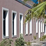 Rose Bay Hotel Santorini mimari, pembe boyalı dış cephe, ferforje pencereler ve palmiye gölgesi
