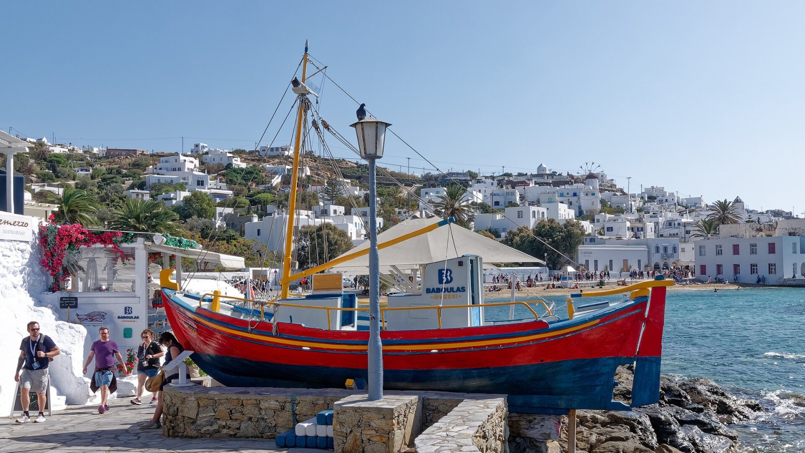 Mykonos limanında geleneksel ahşap kayık ve arkada beyaz kasaba