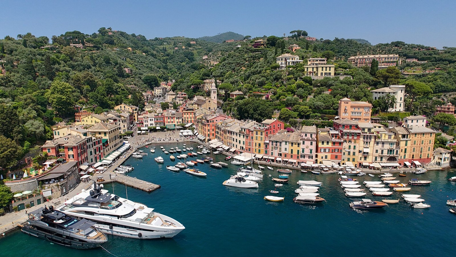 Portofino limanında renkli cepheler, tekneler ve yamaç evleri