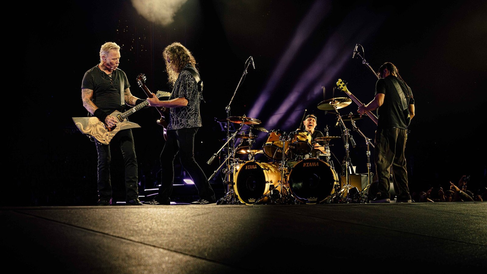 Karanlık sahnede ışık huzmeleri altında konser anı
